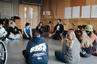 A group of participants sit on the floor of a studio.