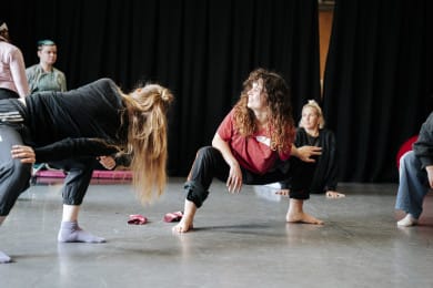 A group of dancers stretching in a studio.