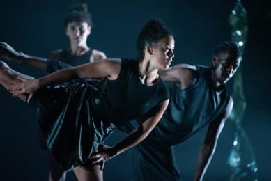 Four dancers on stage against a dark background.